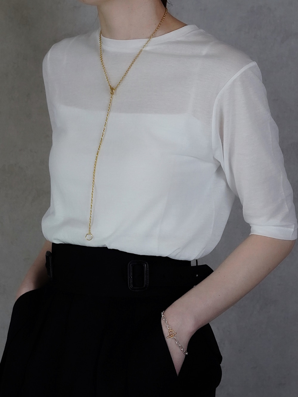 ブラック系のスラックス、ゴールド系のネックレス、シルバー系のブレスレットを着用したレディースの春コーディネートの1枚目の写真