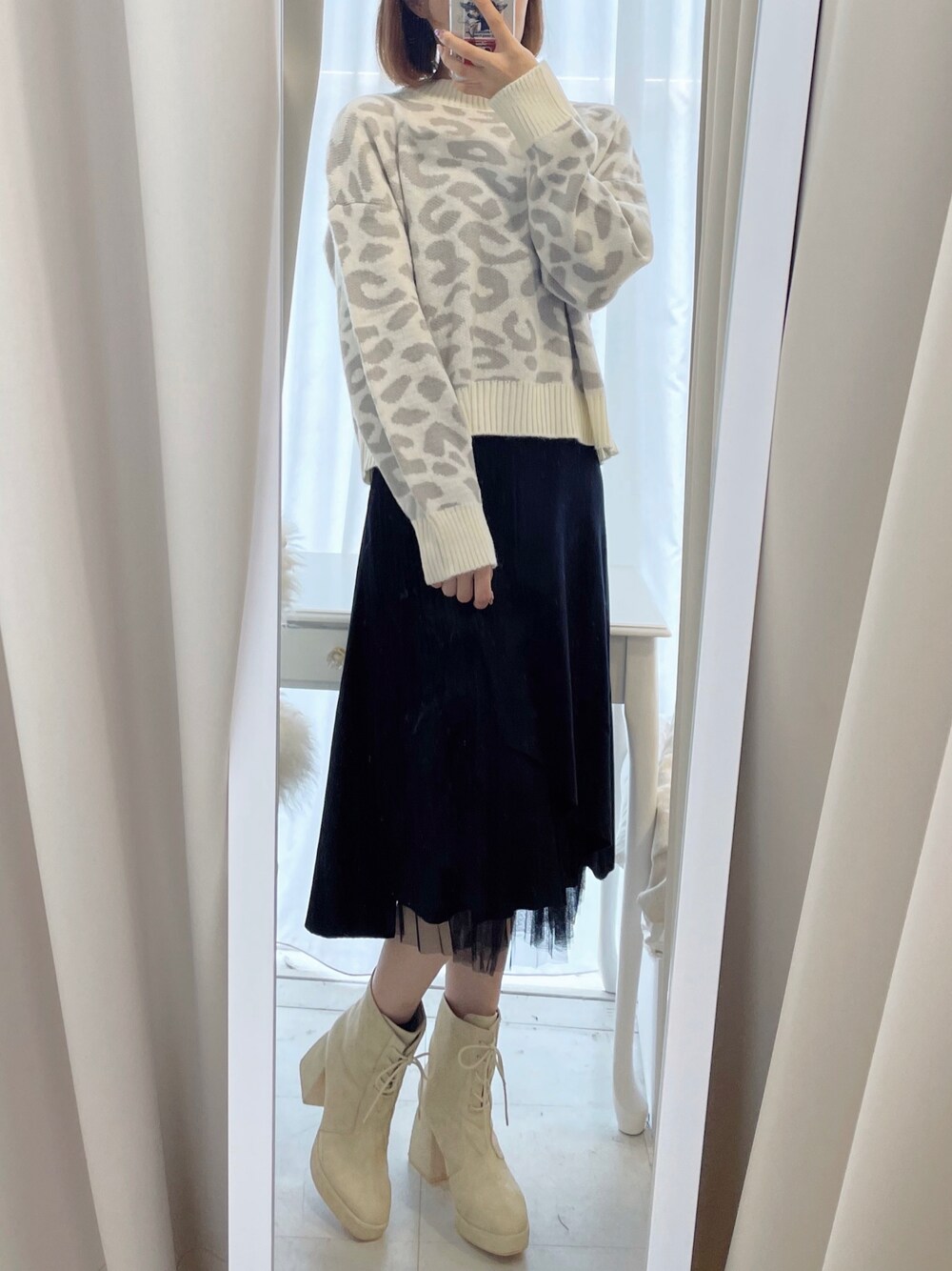 ホワイト系のニット/セーター、ブラック系のスカートを着用したレディースの秋コーディネートの1枚目の写真