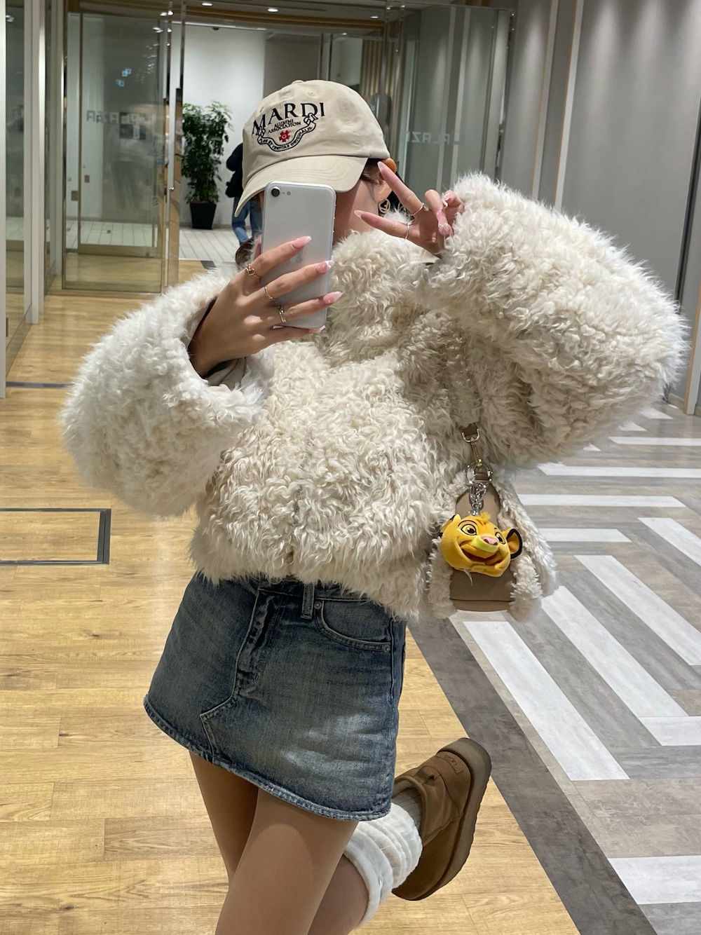 ホワイト系のブルゾン、ベージュ系のショルダーバッグ、ブルー系のデニムスカートを着用したレディースの夏コーディネートの1枚目の写真