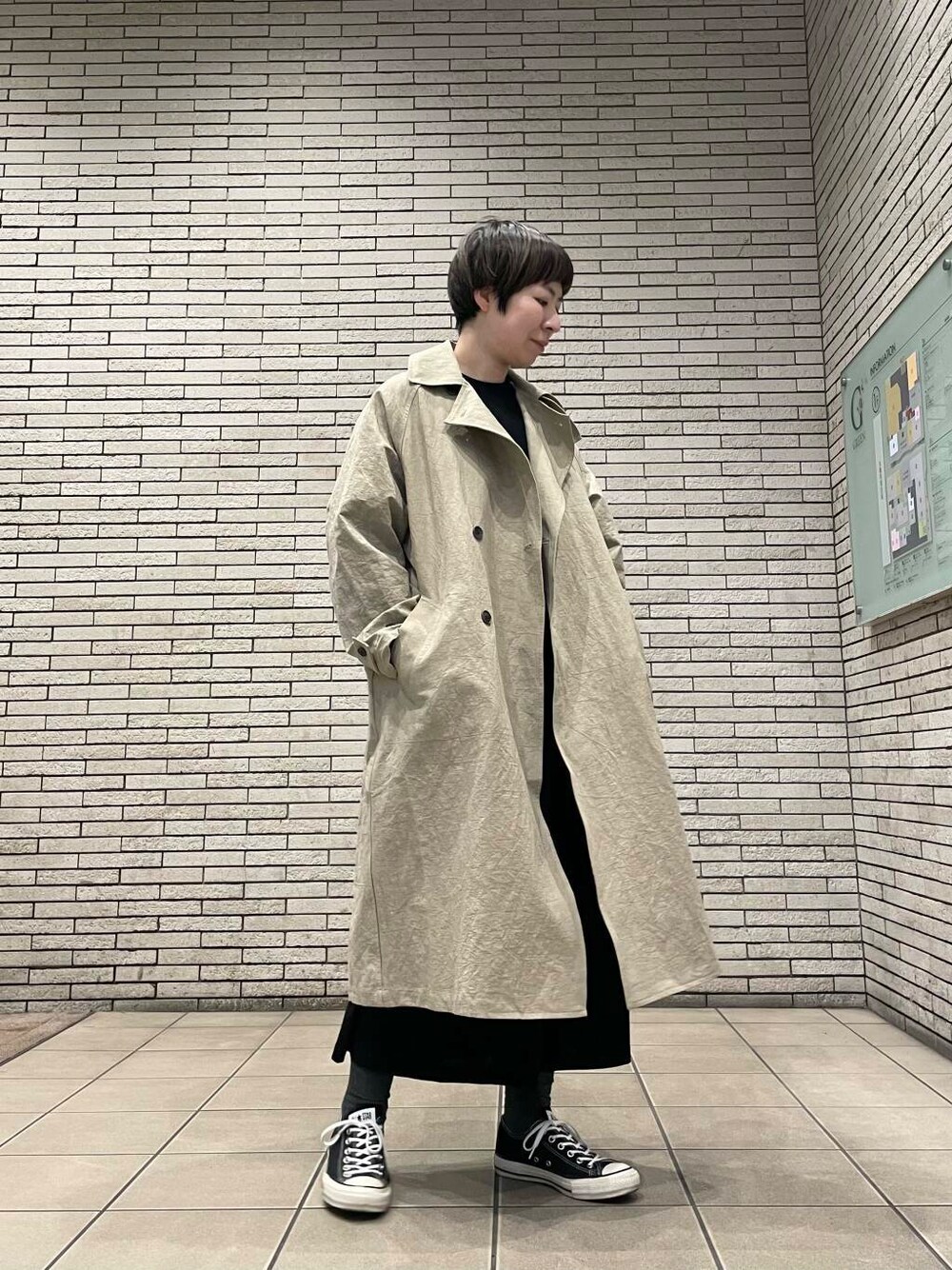 ベージュ系のトレンチコートを着用したレディースの春コーディネートの1枚目の写真