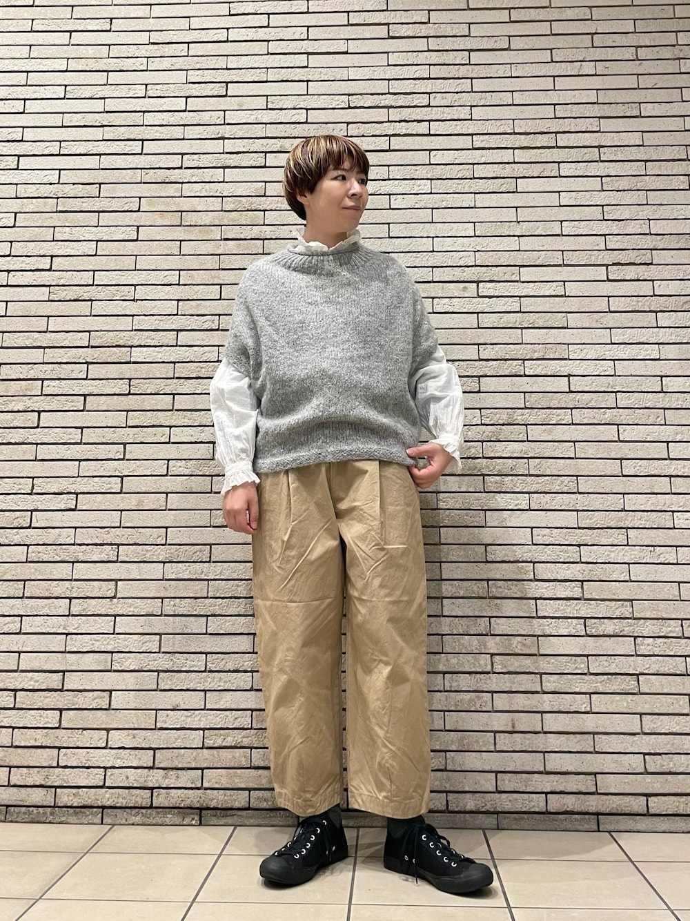 グレー系のニット/セーター、ベージュ系のその他パンツ、ホワイト系のシャツ/ブラウスを着用したレディースの秋コーディネートの1枚目の写真