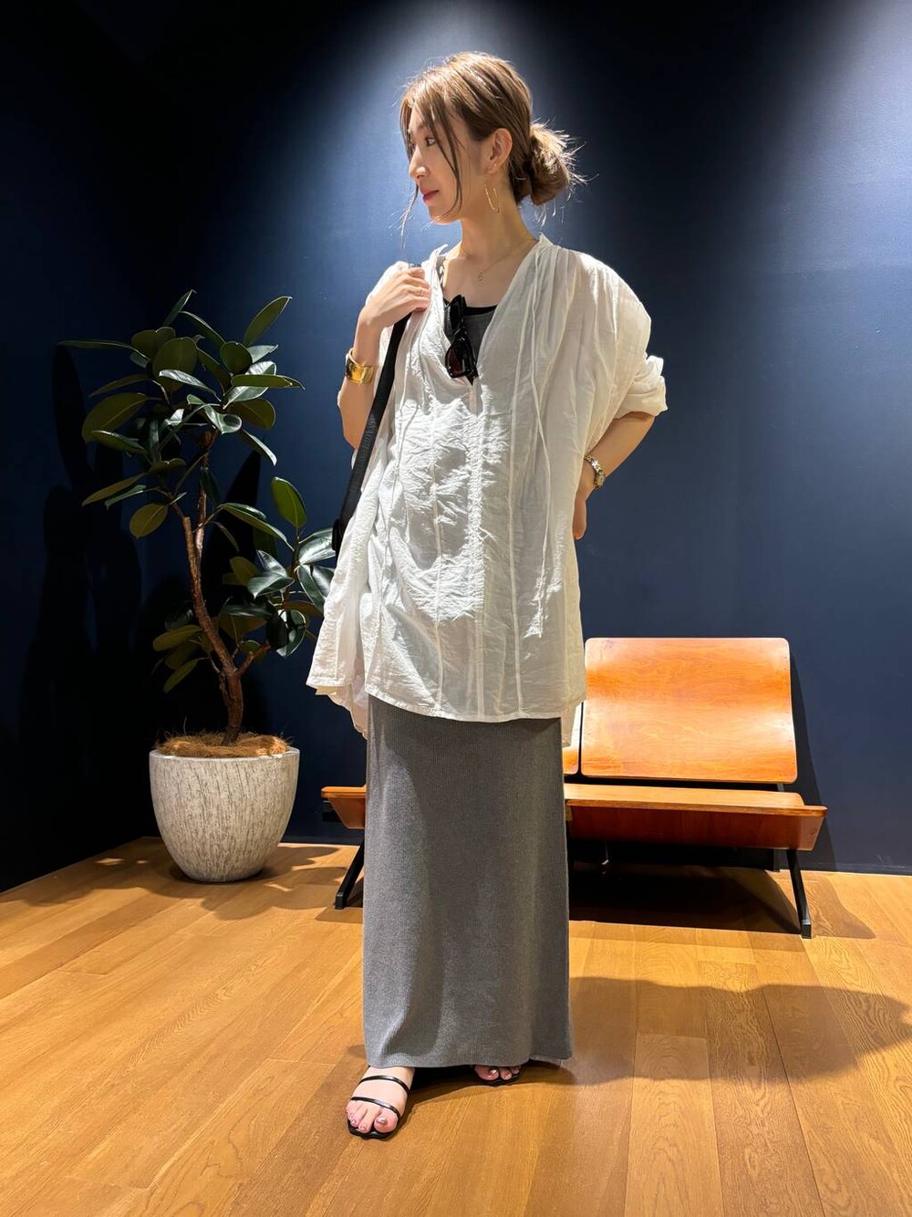 グレー系のスカート、ホワイト系のシャツ/ブラウス、ゴールド系のバングル/リストバンドを着用したレディースの夏コーディネートの1枚目の写真