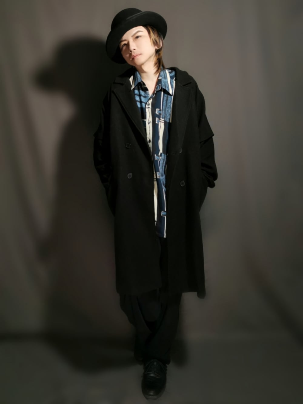 ブラック系のチェスターコート、ブルー系のシャツ/ブラウス、ブラック系のその他パンツを着用したメンズの春コーディネートの1枚目の写真