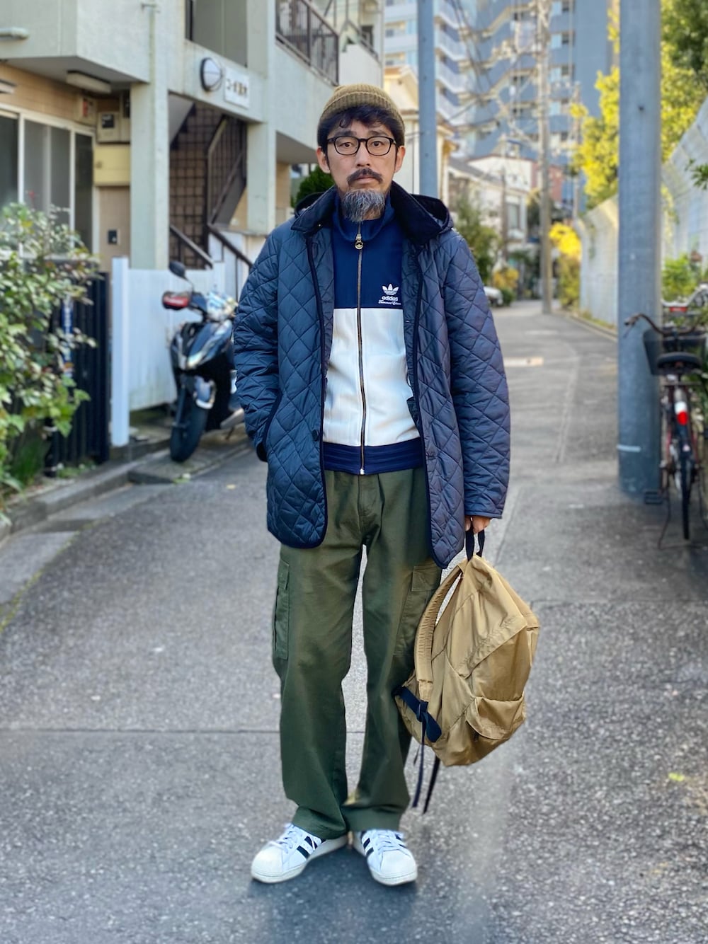 「LAVENHAM、adidas originals、キルティングジャケット、ニット帽、ジャージ、アディダス、カーゴパンツ、スニーカー、冬コーデ、古着MIX、レイヤードスタイル、バックパック、きれいめカジュアル、休日スタイル、ミリタリー」｜「Herve Chapelierのアイテム（バックパック/リュック、ベージュ系）」を使った、ヤギハシカズヒロさん（メンズ・181cm）の冬コーディネートの1枚目の写真
