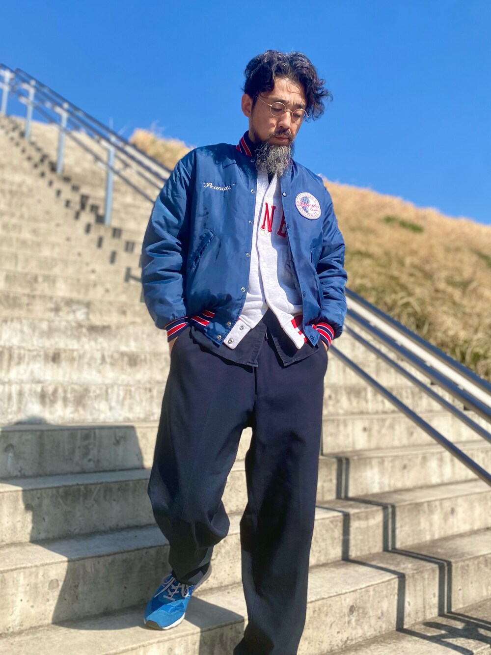 ブルー系のスラックス、ブルー系のスニーカー、ブルー系のスタジャンを着用したメンズの春コーディネートの1枚目の写真