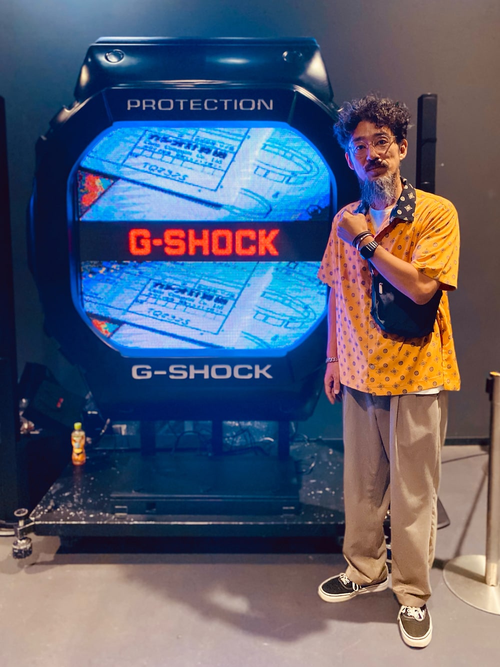 ベージュ系のスラックス、ブラック系のスニーカー、ブラック系のショルダーバッグを着用したメンズの秋コーディネートの1枚目の写真