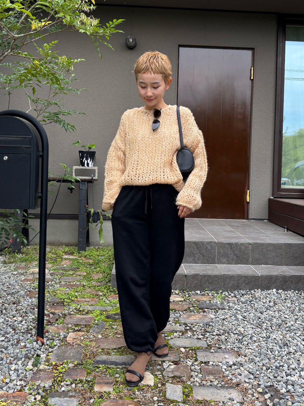 オレンジ系のニット/セーター、ブラック系のその他パンツ、ブラック系のサンダルを着用したレディースの秋コーディネートの1枚目の写真