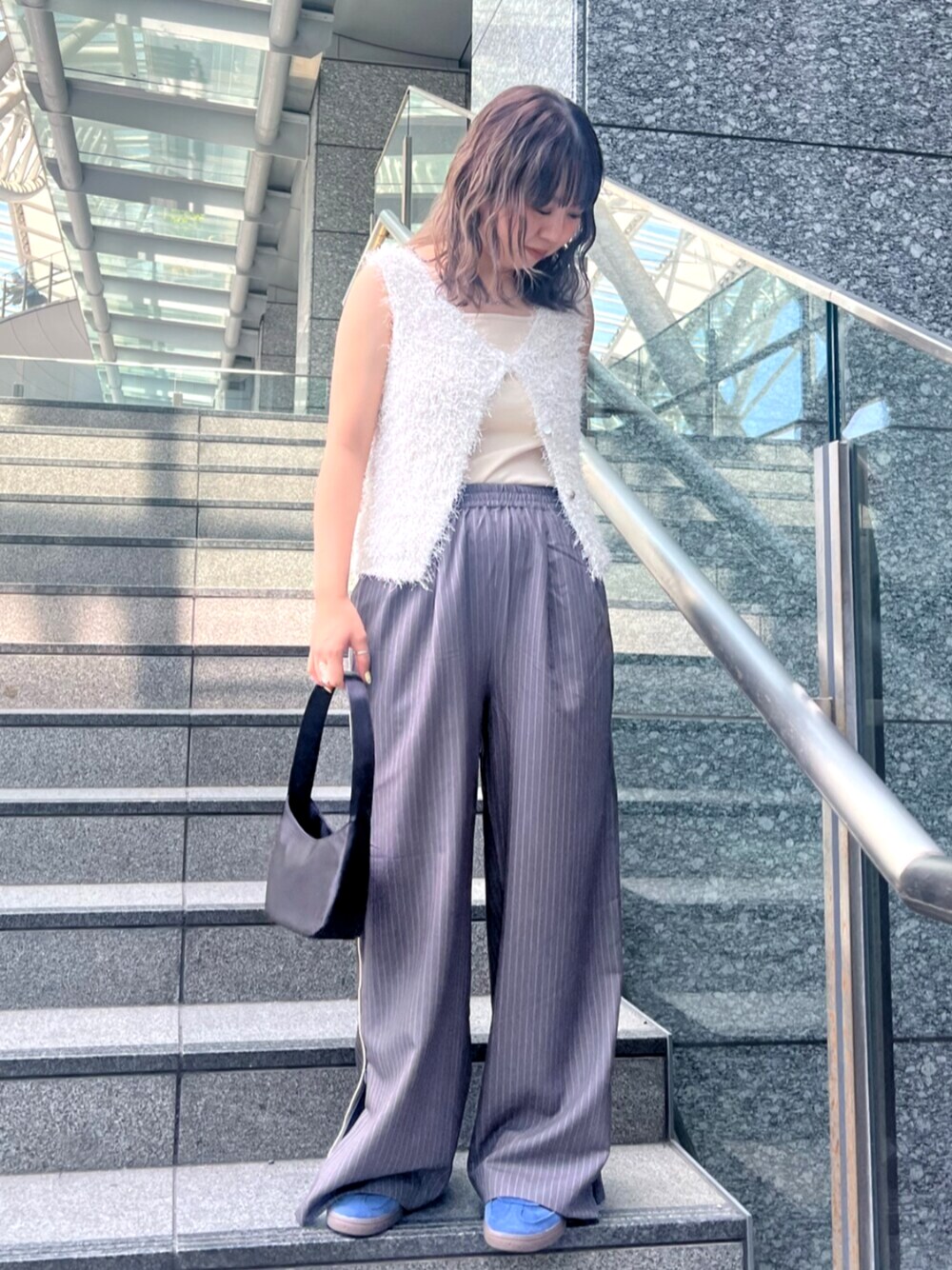 グレー系のその他パンツ、ホワイト系のベスト、ホワイト系のキャミソールを着用したレディースの春コーディネートの1枚目の写真