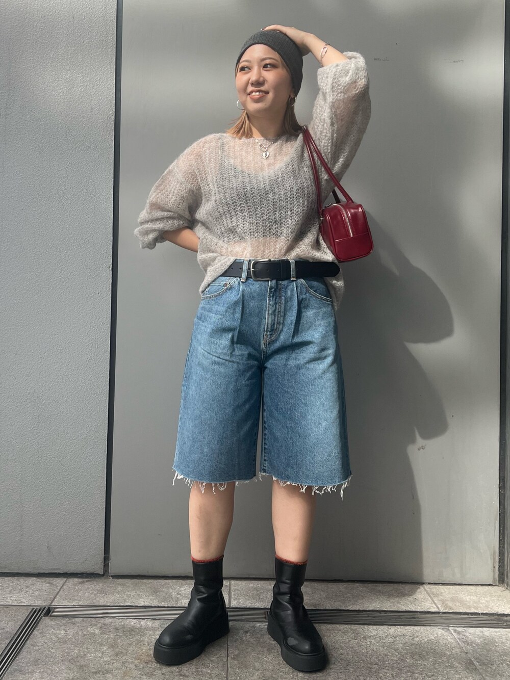 ブルー系のデニムパンツ、グレー系のニット/セーター、レッド系のハンドバッグを着用したレディースの秋コーディネートの1枚目の写真