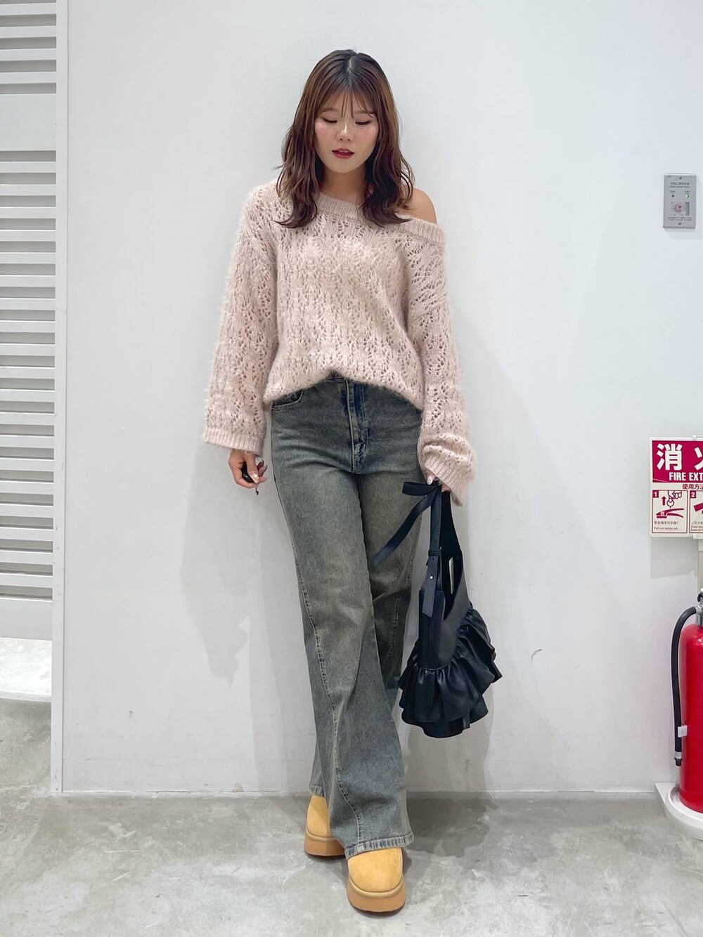 イエロー系のブーツ、ピンク系のニット/セーター、ブルー系のデニムパンツを着用したレディースの秋コーディネートの1枚目の写真