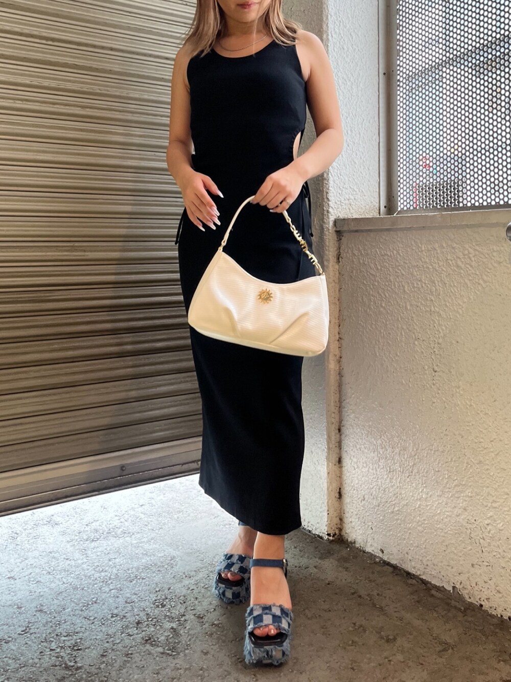 ブラック系のワンピース、ホワイト系のハンドバッグ、ブルー系のサンダルを着用したレディースの夏コーディネートの1枚目の写真