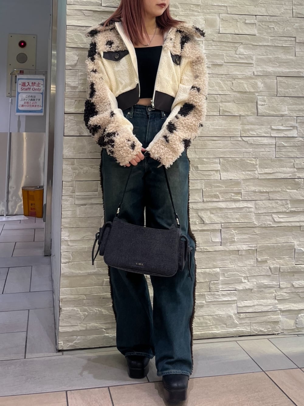 ブラウン系のブルゾン、ブルー系のデニムパンツ、ブラック系のハンドバッグを着用したレディースの秋コーディネートの1枚目の写真