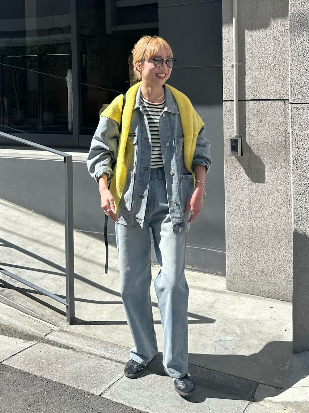 ブルー系のデニムジャケット、ブルー系のデニムパンツ、イエロー系のニット/セーターを着用したレディースの春コーディネートの1枚目の写真
