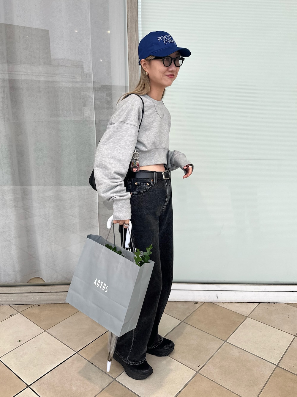 グレー系のスウェット、ブラック系のデニムパンツ、ブラック系のスニーカーを着用したレディースの秋コーディネートの1枚目の写真