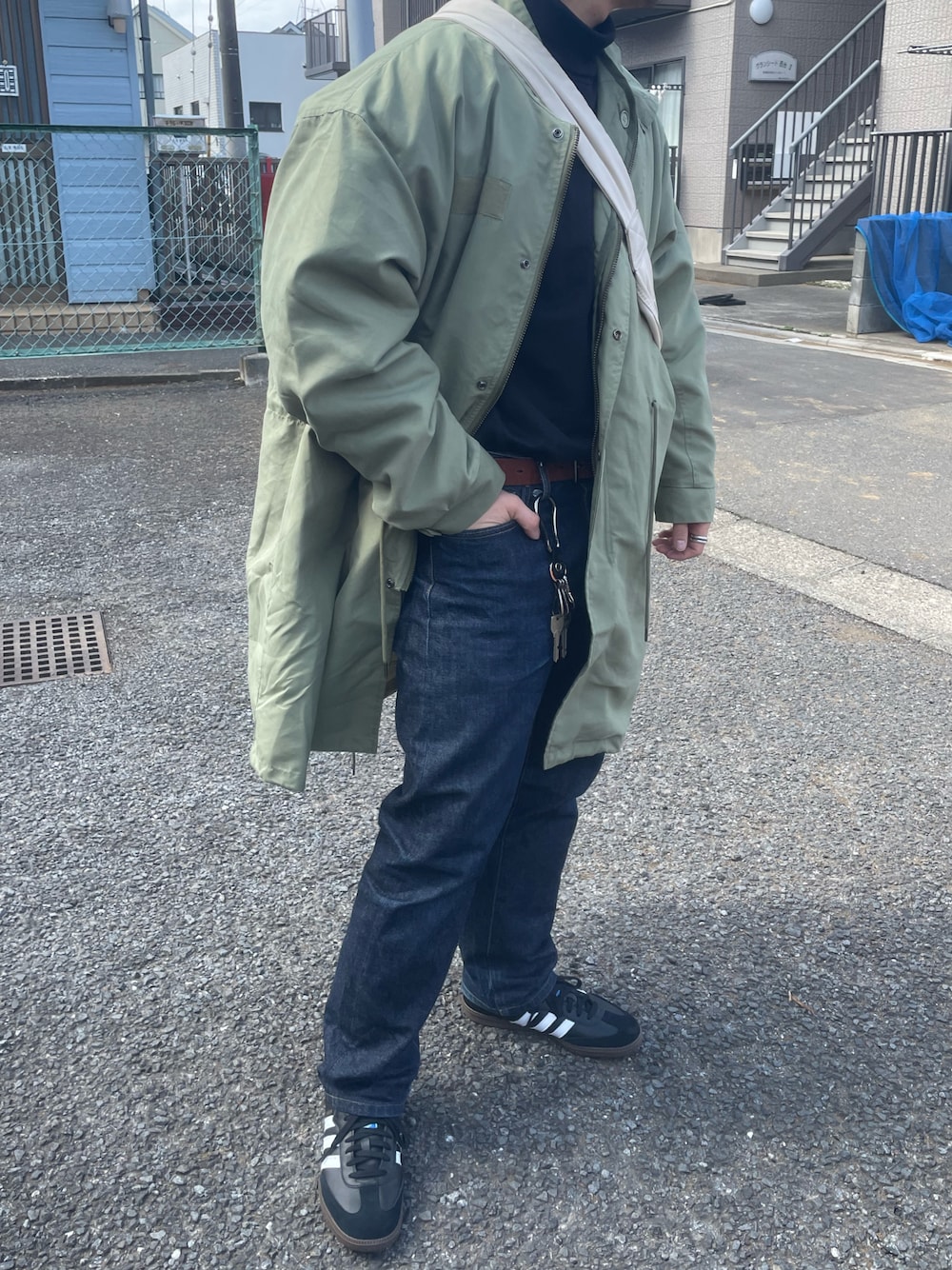 ブラック系のスニーカー、ブラック系のニット/セーター、ブルー系のデニムパンツを着用したメンズの春コーディネートの1枚目の写真