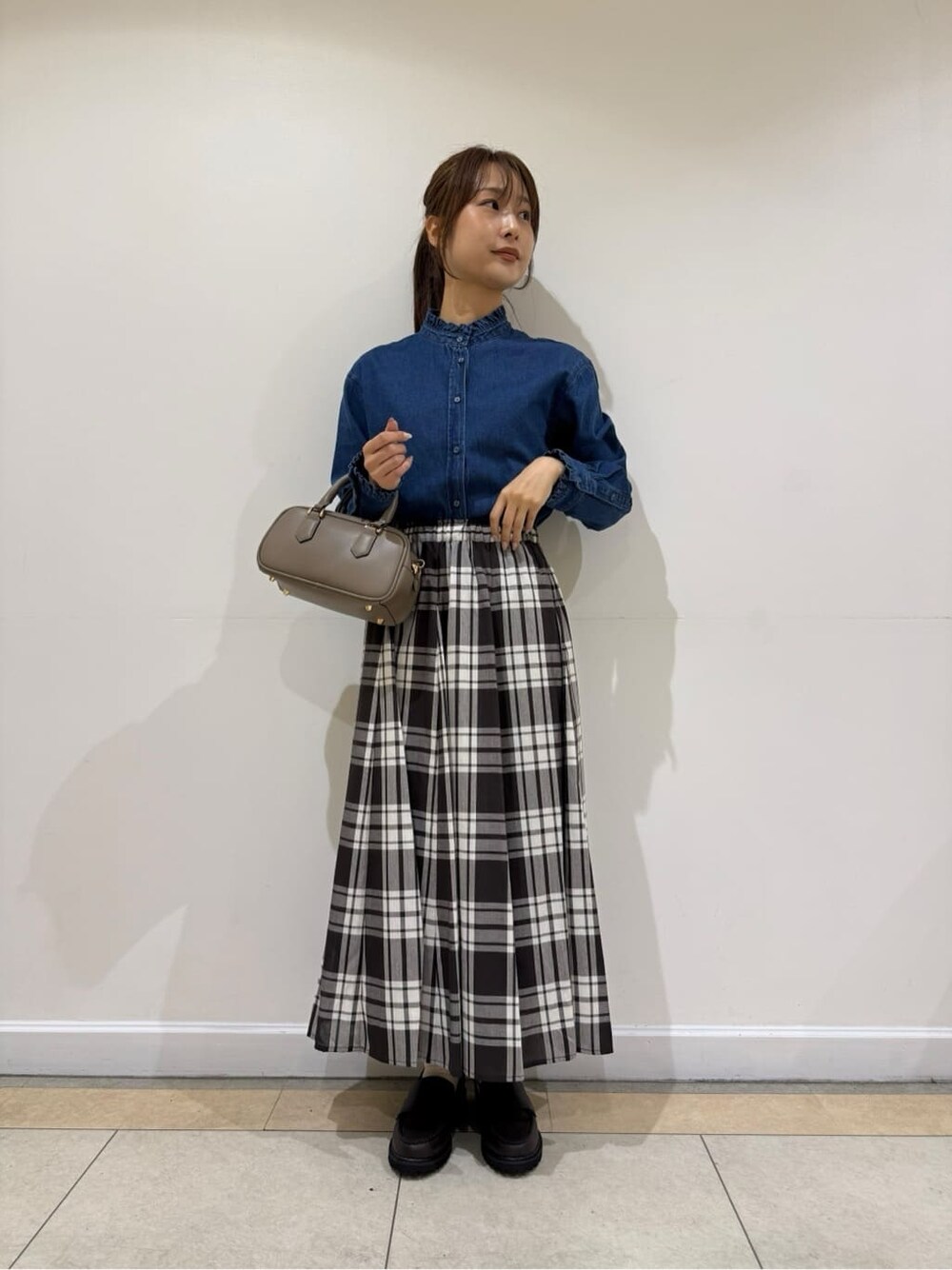 ブラウン系のスカート、ブラウン系のパンプス、ブラウン系のショルダーバッグを着用したレディースの秋コーディネートの1枚目の写真