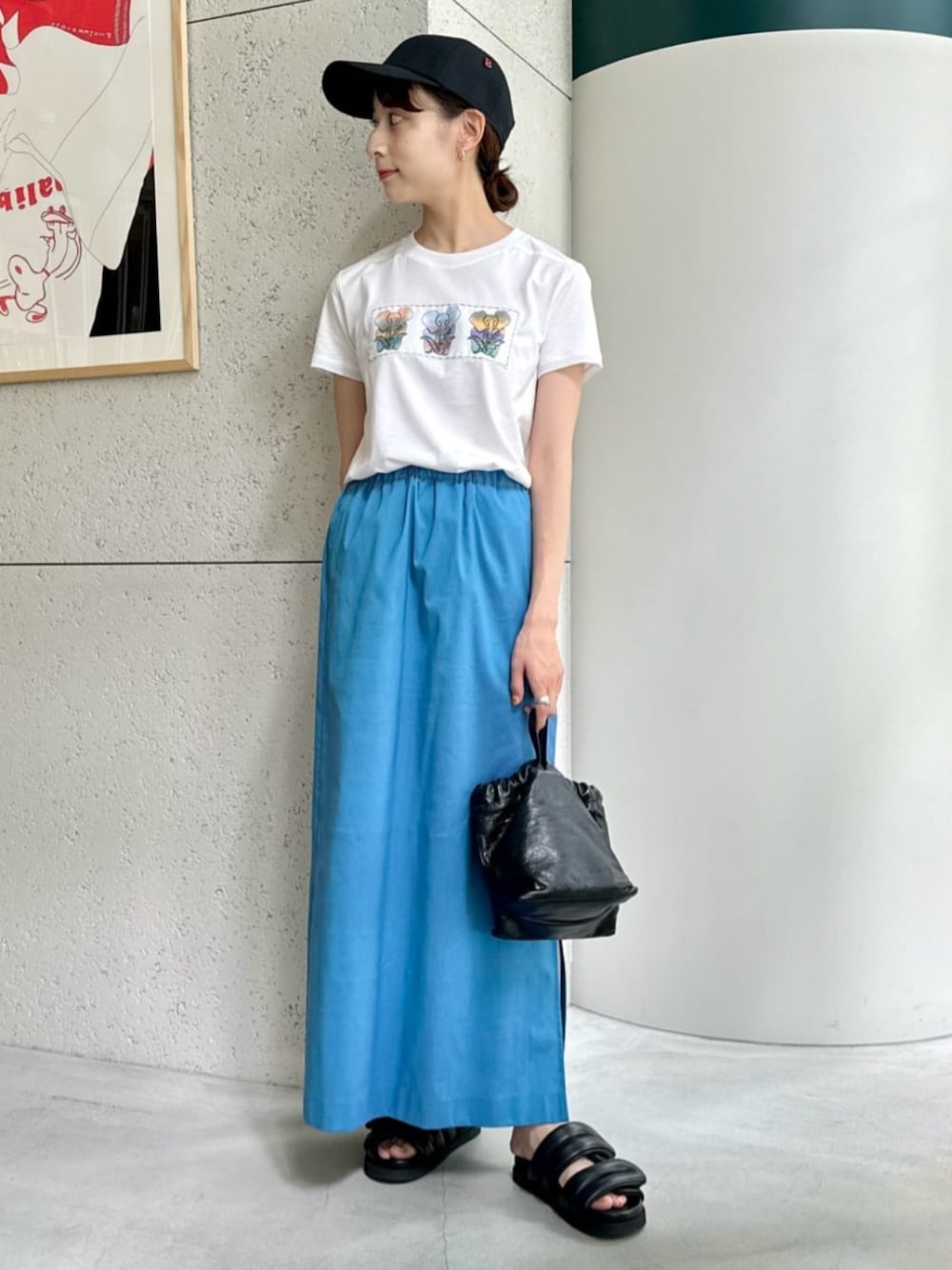 ブラック系のショルダーバッグ、ブラック系のサンダル、ブルー系のスカートを着用したレディースの夏コーディネートの1枚目の写真