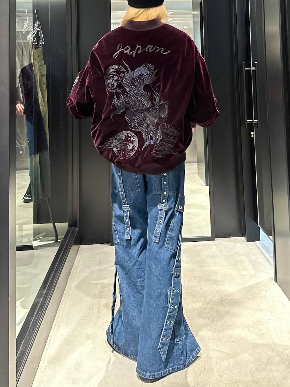 レッド系のブルゾン、ブラック系のその他シューズ、ブルー系のデニムパンツを着用したメンズの秋コーディネートの1枚目の写真