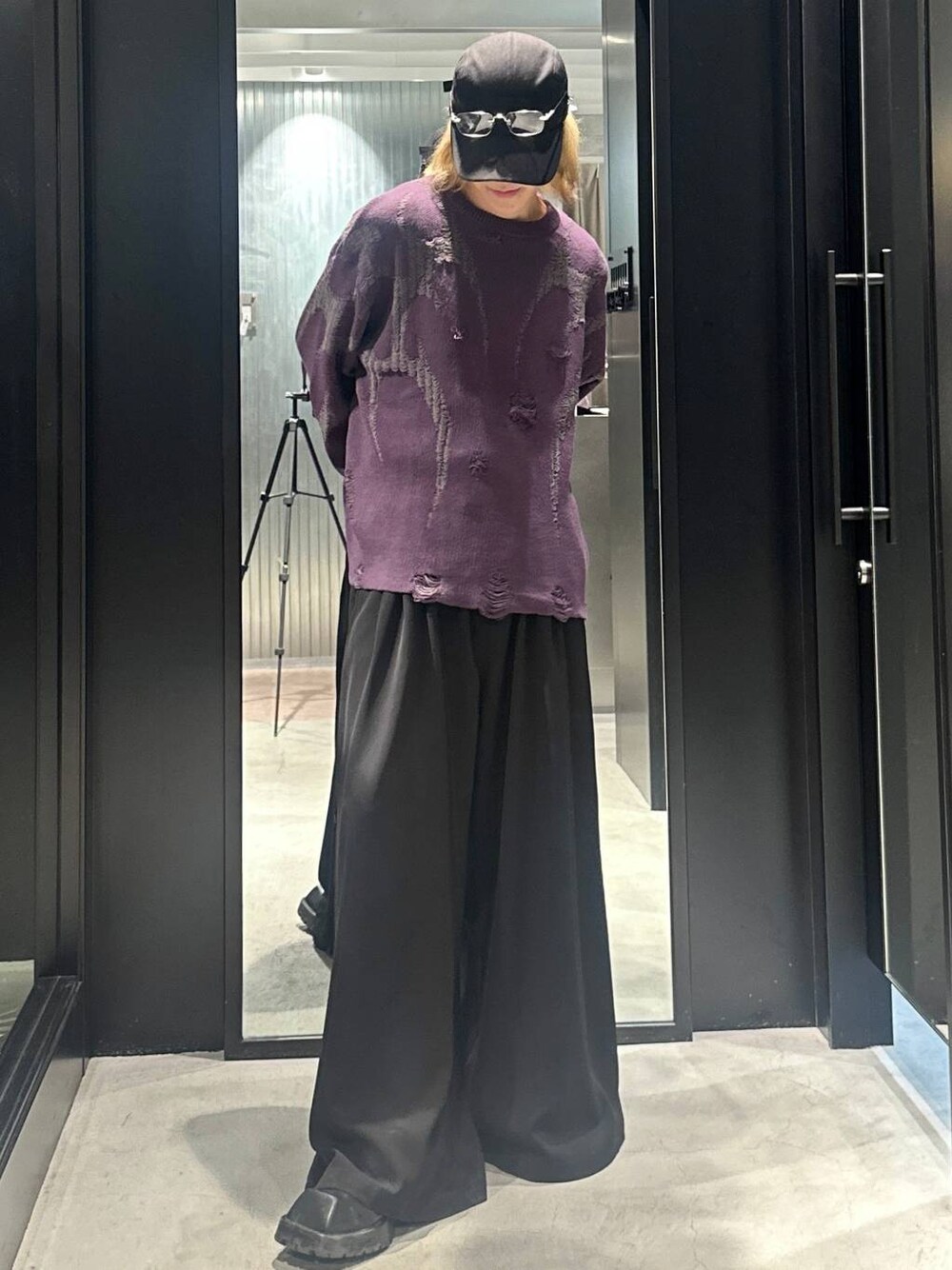 パープル系のニット/セーター、ブラック系のスラックス、ブラック系のキャップを着用したメンズの秋コーディネートの1枚目の写真