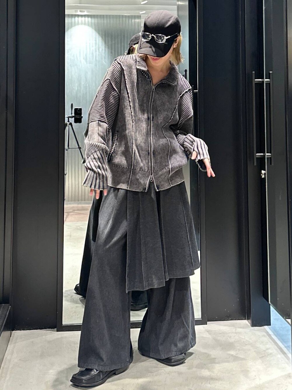 グレー系のスラックス、ブラック系のニット/セーター、ブラック系のキャップを着用したメンズの秋コーディネートの1枚目の写真