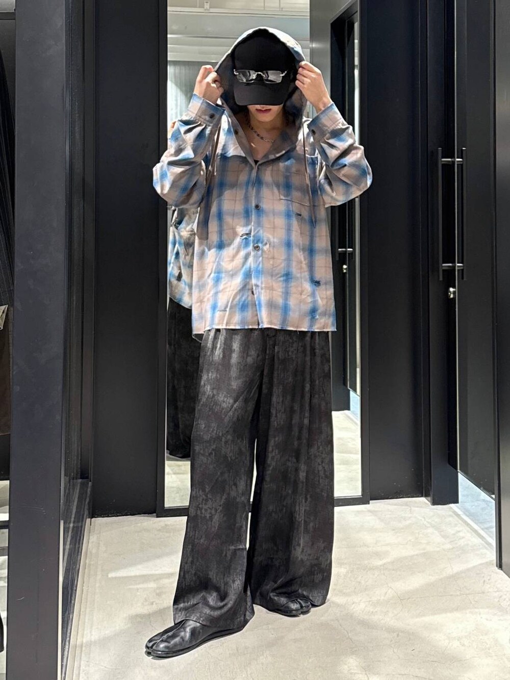 ブラック系のTシャツ/カットソー、グレー系のスラックス、ブラック系のキャップを着用したメンズの冬コーディネートの1枚目の写真