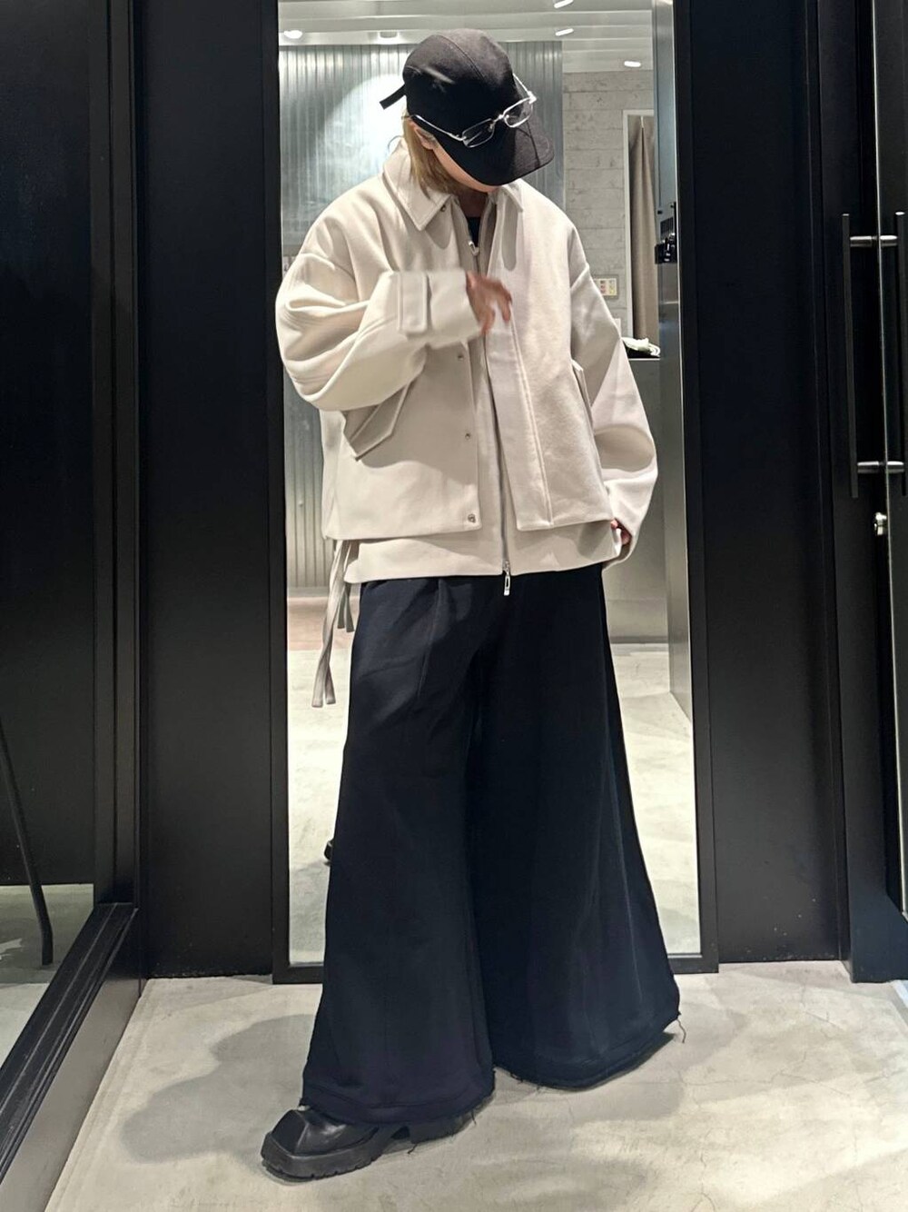 ブラック系のスウェットパンツ、ホワイト系のブルゾン、ブラック系のキャップを着用したメンズの秋コーディネートの1枚目の写真