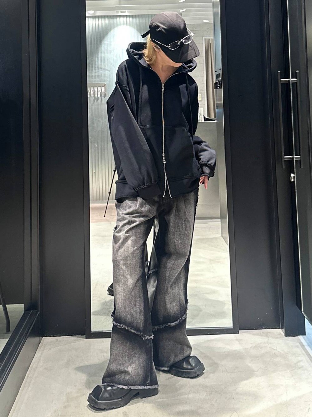 ブラック系のデニムパンツ、ブラック系のパーカー、ブラック系のキャップを着用したメンズの秋コーディネートの1枚目の写真