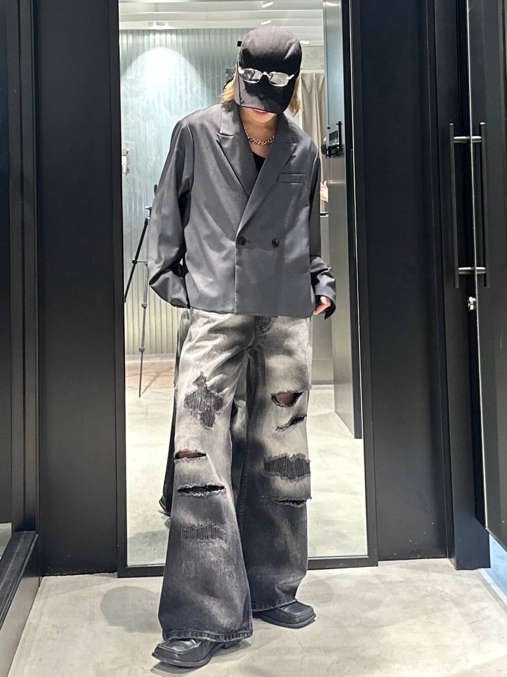 グレー系のテーラードジャケット、ブラック系のデニムパンツ、ブラック系のキャップを着用したメンズの秋コーディネートの1枚目の写真