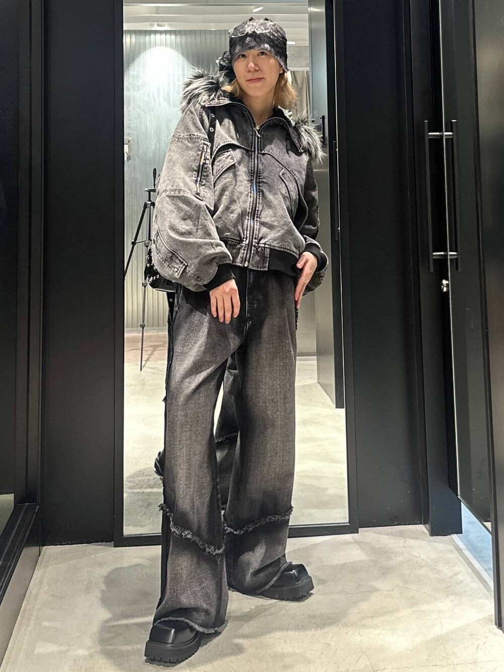 ブラック系のデニムパンツ、ブラック系のショルダーバッグ、グレー系のブルゾンを着用したメンズの秋コーディネートの1枚目の写真