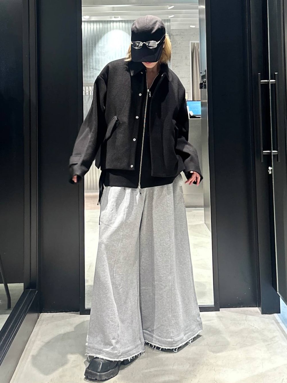 グレー系のスウェットパンツ、ブラック系のブルゾン、ブラック系のキャップを着用したメンズの秋コーディネートの1枚目の写真