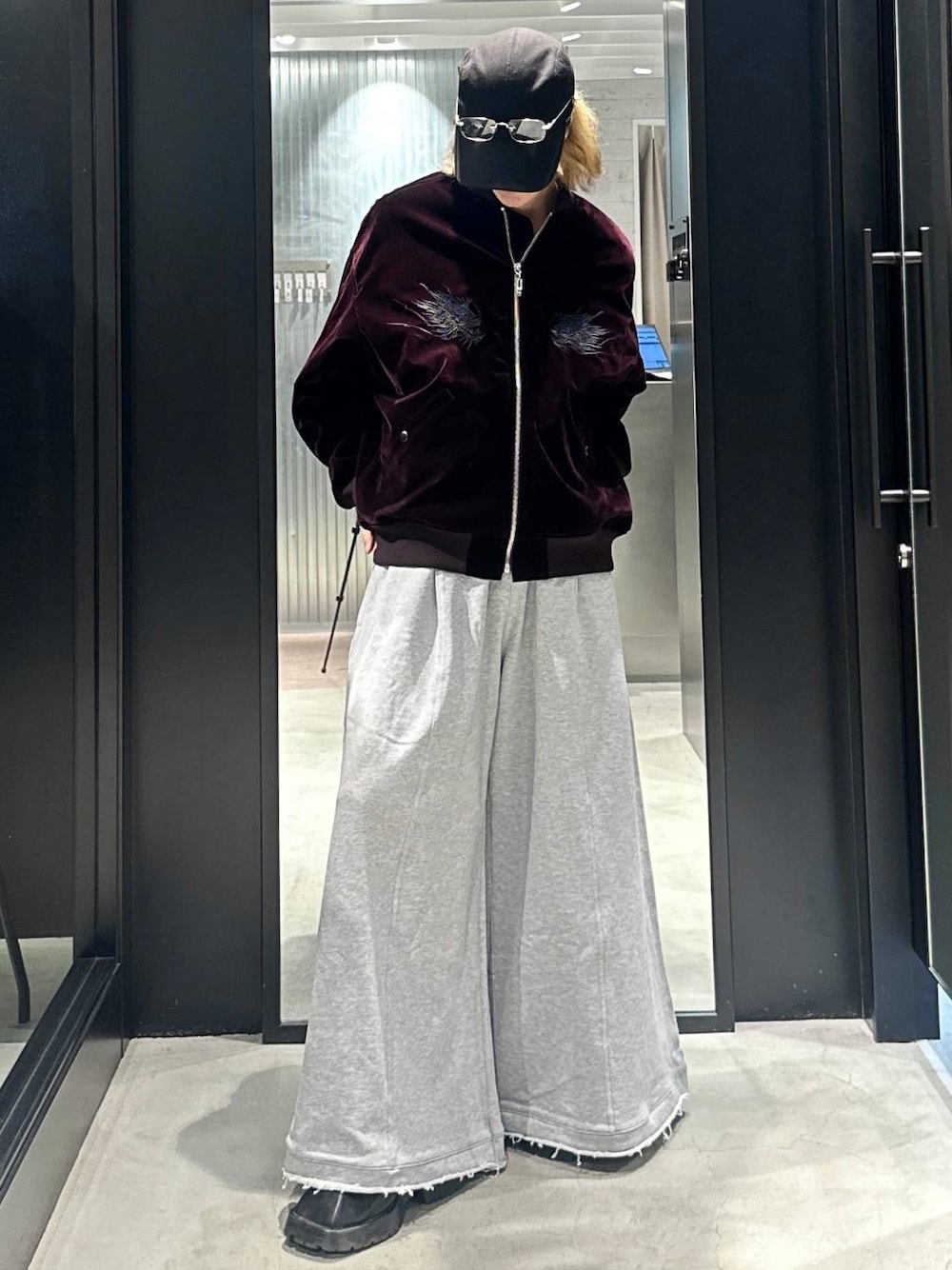 グレー系のスウェットパンツ、レッド系のブルゾン、ブラック系のキャップを着用したメンズの秋コーディネートの1枚目の写真