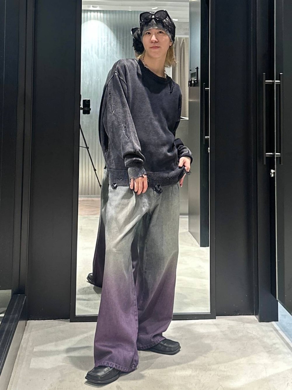 パープル系のデニムパンツ、ブラック系のニット/セーター、シルバー系のネックレスを着用したメンズの秋コーディネートの1枚目の写真
