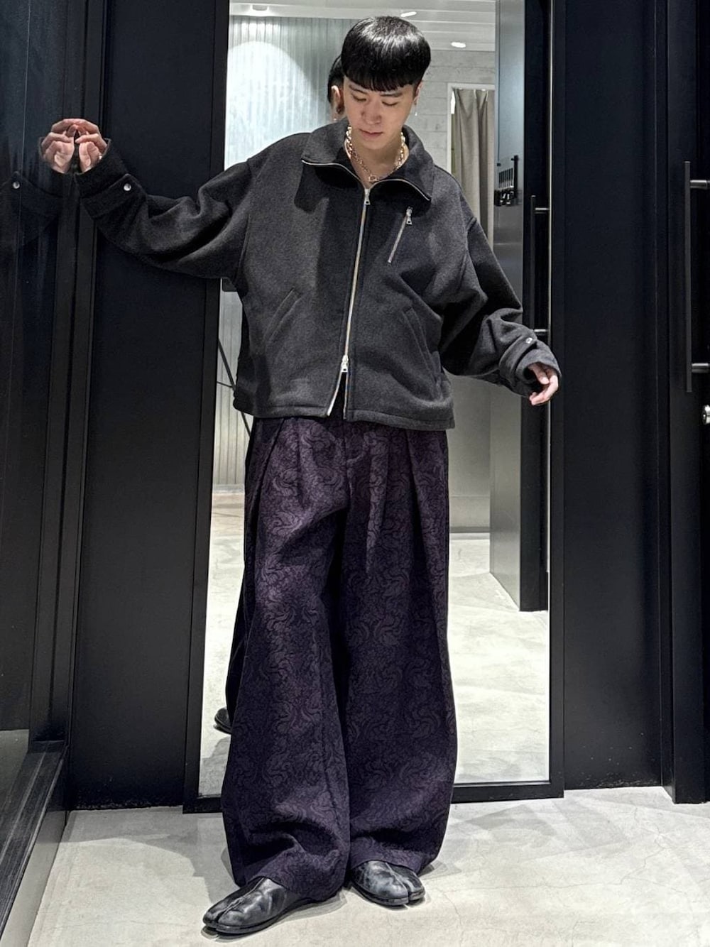 グレー系のブルゾン、パープル系のスラックスを着用したメンズの秋コーディネートの1枚目の写真