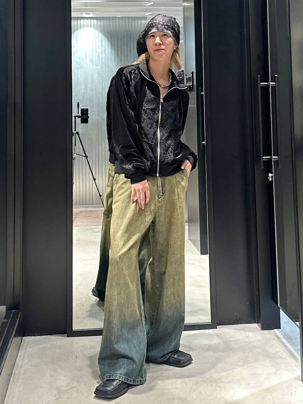 グリーン系のデニムパンツ、ブラック系のブルゾン、シルバー系のネックレスを着用したメンズの秋コーディネートの1枚目の写真