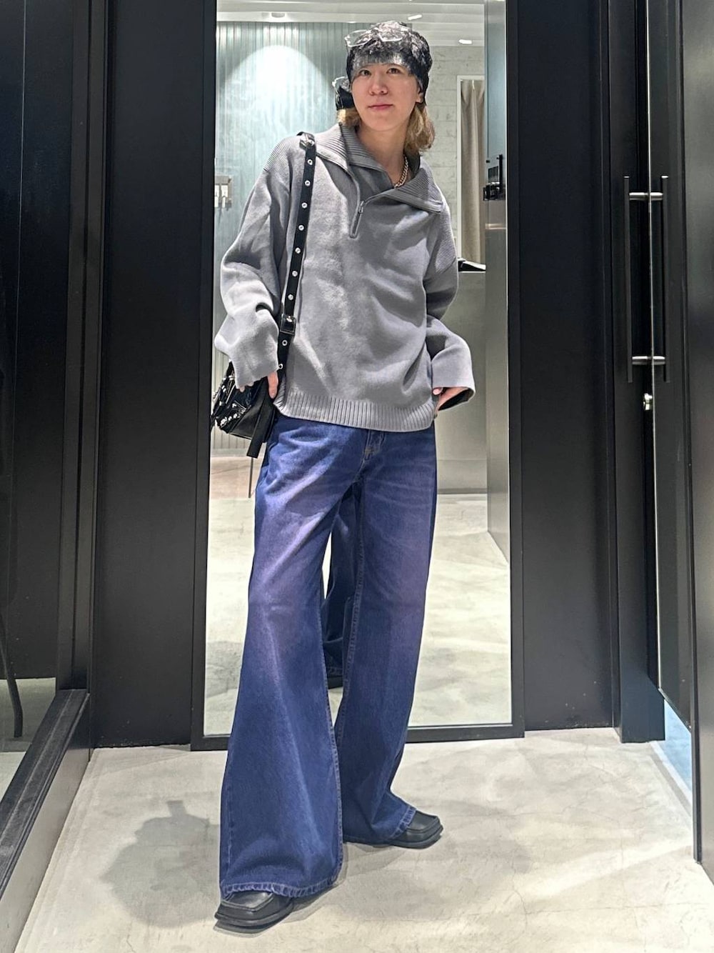 パープル系のデニムパンツ、グレー系のニット/セーター、ブラック系のショルダーバッグを着用したメンズの秋コーディネートの1枚目の写真