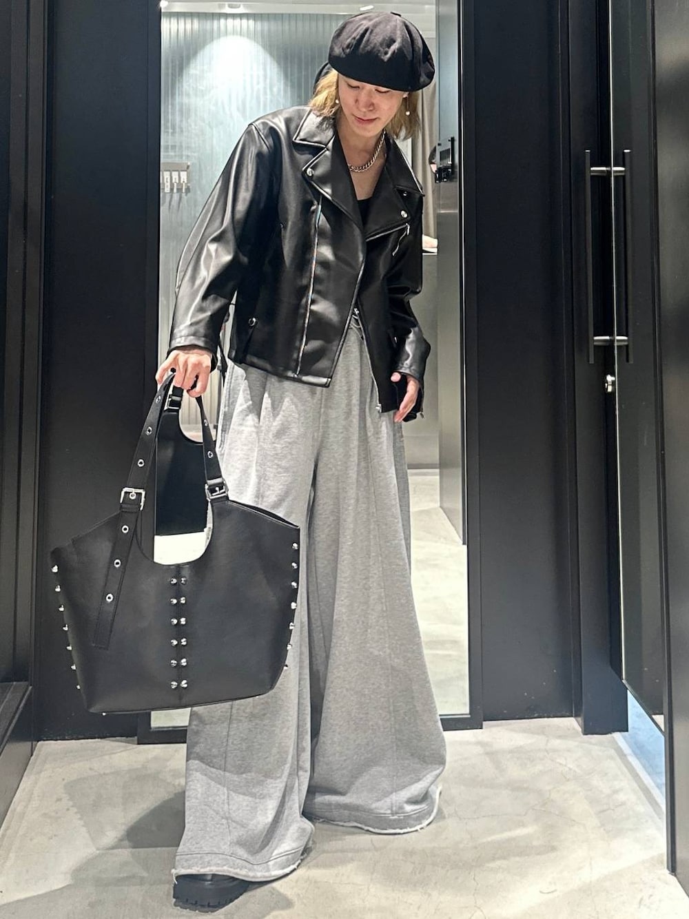 グレー系のスウェットパンツ、ブラック系のライダースジャケット、ブラック系のトートバッグを着用したメンズの秋コーディネートの1枚目の写真