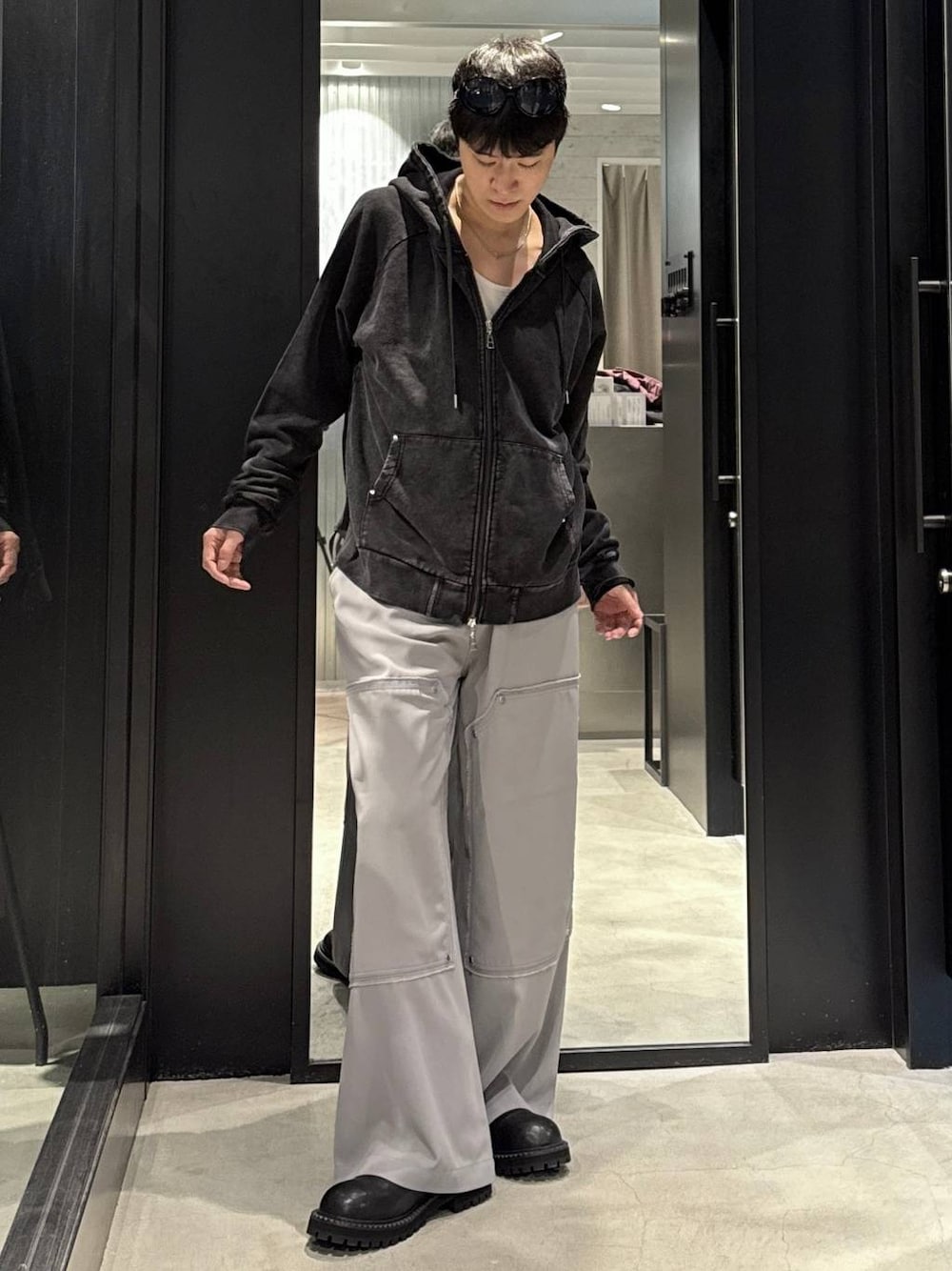 ブラック系のパーカー、ブラック系のブーツ、シルバー系のネックレスを着用したメンズの秋コーディネートの1枚目の写真