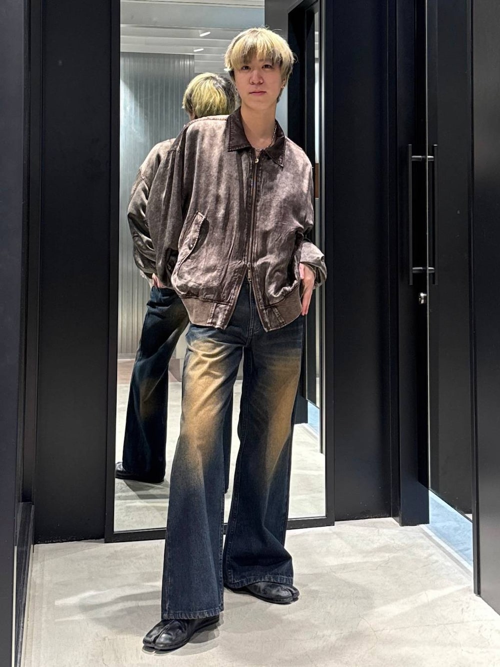 ブルー系のデニムパンツ、ブラック系のTシャツ/カットソー、ブラウン系のブルゾンを着用したメンズの冬コーディネートの1枚目の写真