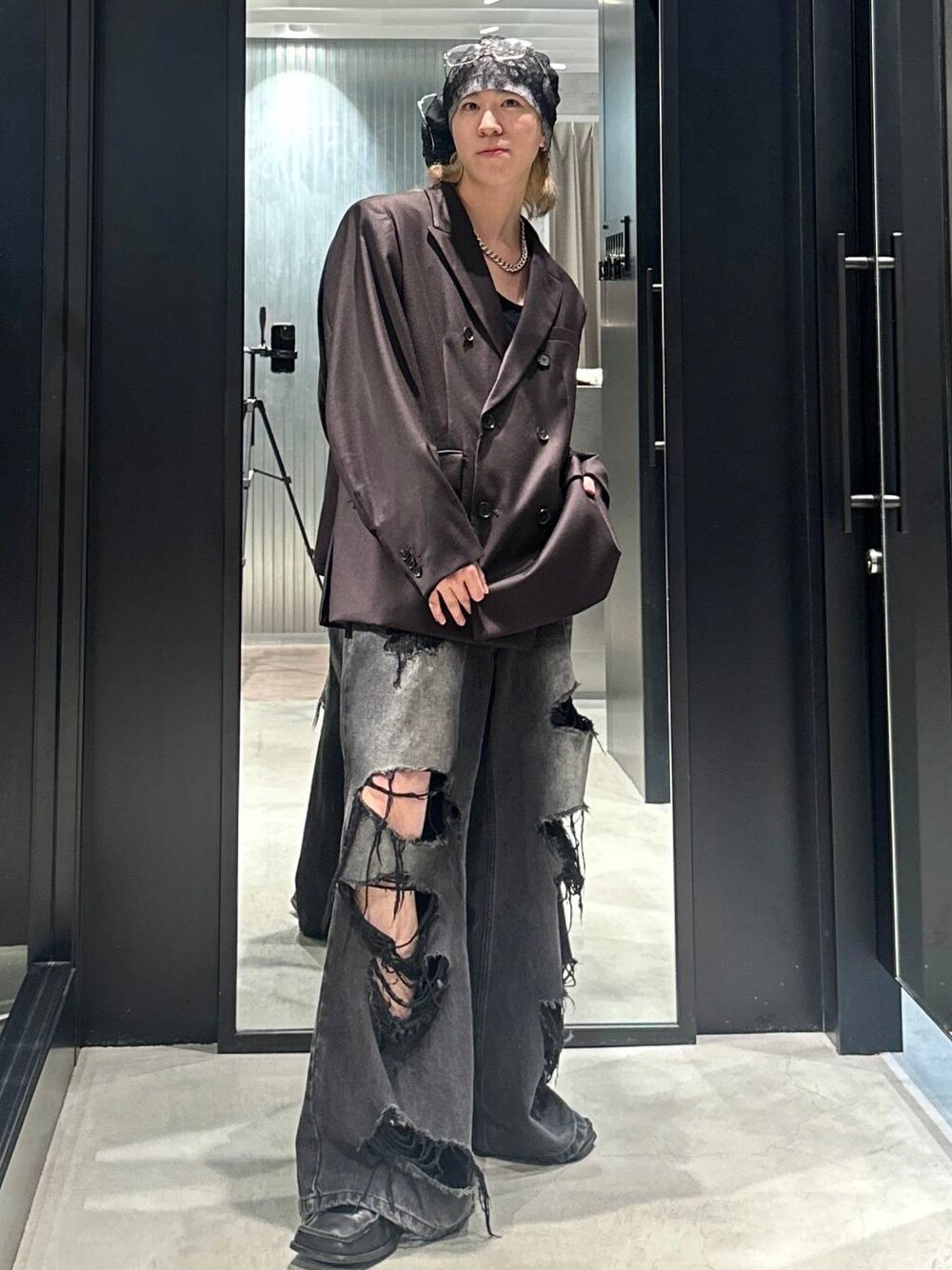 ブラック系のデニムパンツ、ブラウン系のテーラードジャケット、シルバー系のネックレスを着用したメンズの秋コーディネートの1枚目の写真