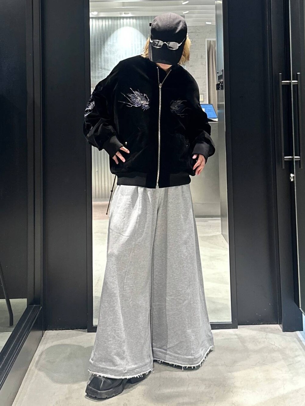 グレー系のスウェットパンツ、ブラック系のブルゾン、ブラック系のキャップを着用したメンズの秋コーディネートの1枚目の写真