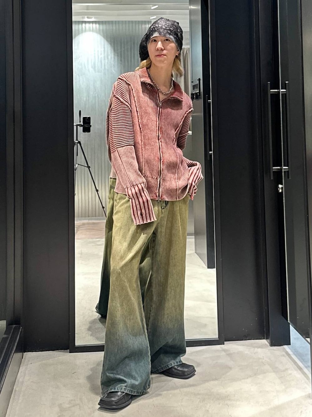 グリーン系のデニムパンツ、オレンジ系のニット/セーター、シルバー系のネックレスを着用したメンズの秋コーディネートの1枚目の写真