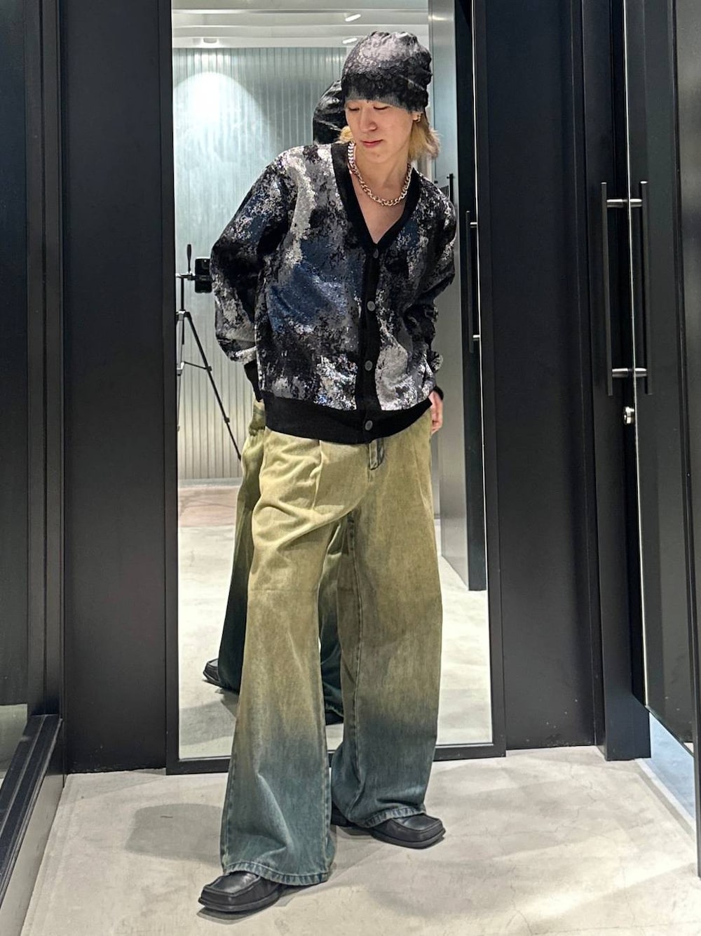 グリーン系のデニムパンツ、ブラック系のカーディガン/ボレロ、シルバー系のネックレスを着用したメンズの秋コーディネートの1枚目の写真