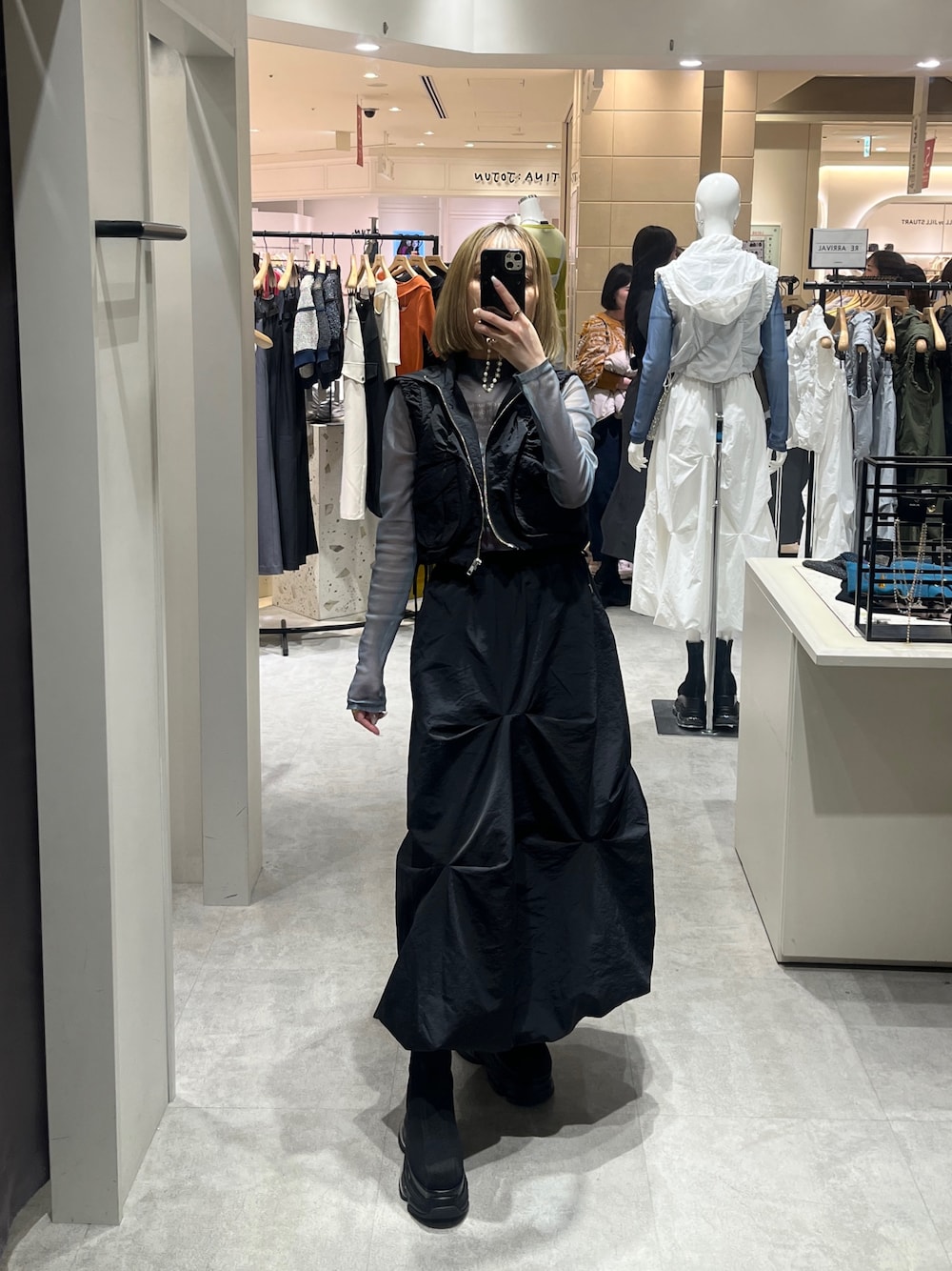 ブラック系のスカート、ブラック系のブーツ、グリーン系のTシャツ/カットソーを着用したレディースの春コーディネートの1枚目の写真