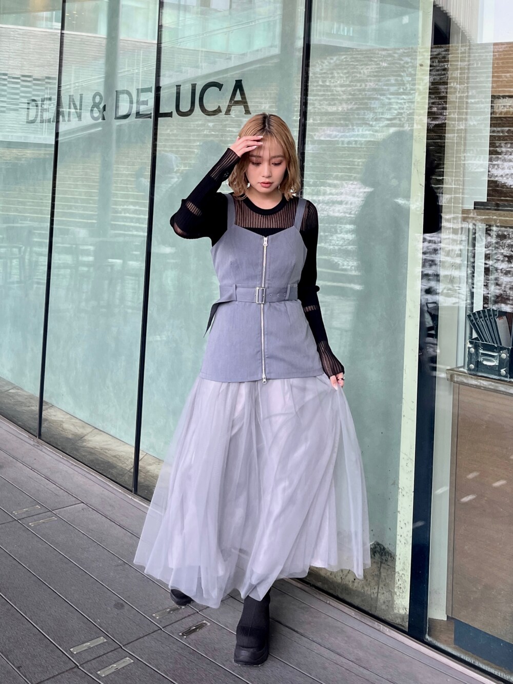 ブラック系のニット/セーター、グレー系のジャンパースカート、ブラック系のブーツを着用したレディースの春コーディネートの1枚目の写真