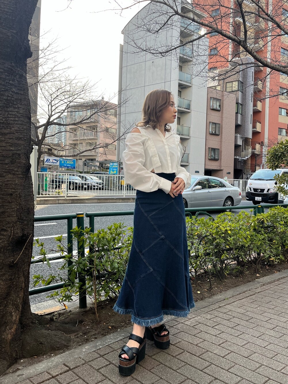 ホワイト系のシャツ/ブラウス、ブルー系のデニムスカート、ブラック系のサンダルを着用したレディースの春コーディネートの1枚目の写真