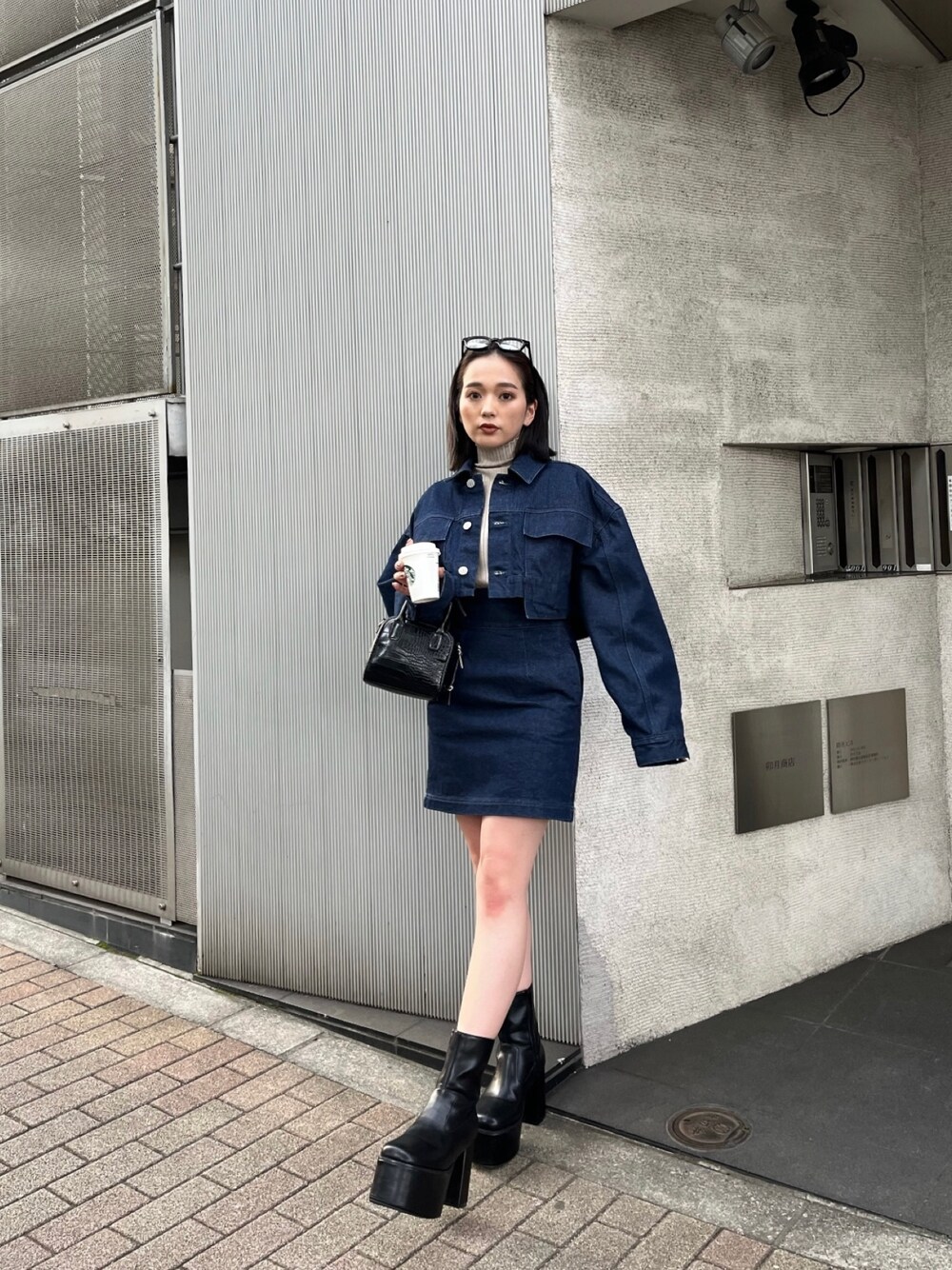 ブラック系のボストンバッグ、ブラック系のブーツ、ブルー系のデニムジャケットを着用したレディースの夏コーディネートの1枚目の写真