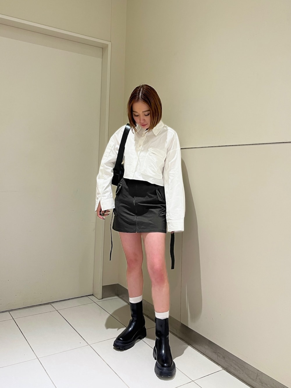 ホワイト系のシャツ/ブラウス、グリーン系のスカート、ブラック系のブーツを着用したレディースの冬コーディネートの1枚目の写真