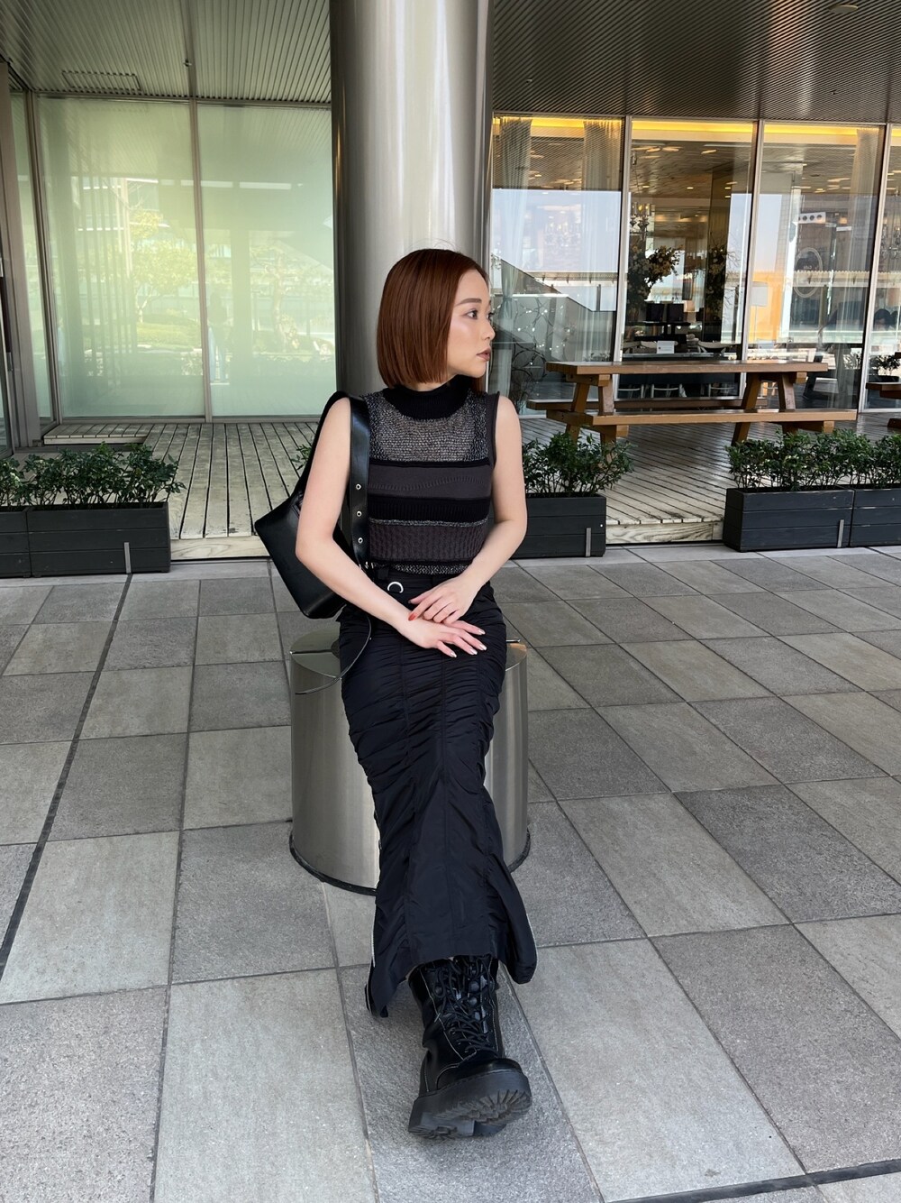 ブラック系のニット/セーター、ブラック系のスカート、ブラック系のショルダーバッグを着用したレディースの春コーディネートの1枚目の写真