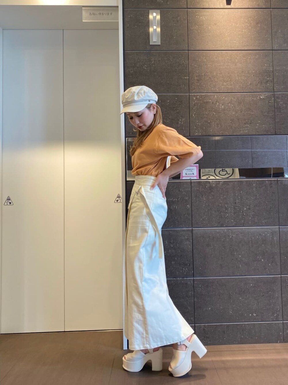 ホワイト系のスカート、オレンジ系のTシャツ/カットソー、ホワイト系のサンダルを着用したレディースの春コーディネートの1枚目の写真