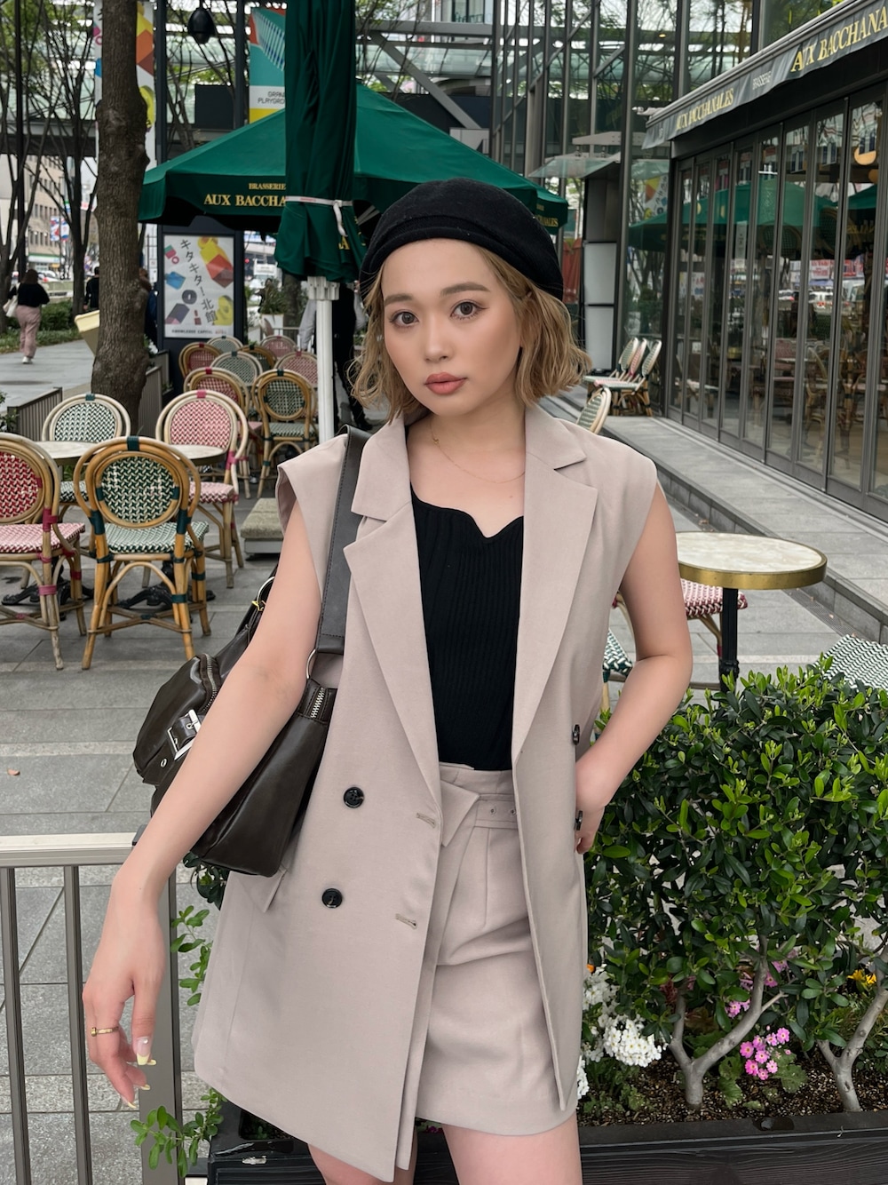 ブラック系のタンクトップ、ベージュ系のベスト、ブラウン系のハンドバッグを着用したレディースの春コーディネートの1枚目の写真